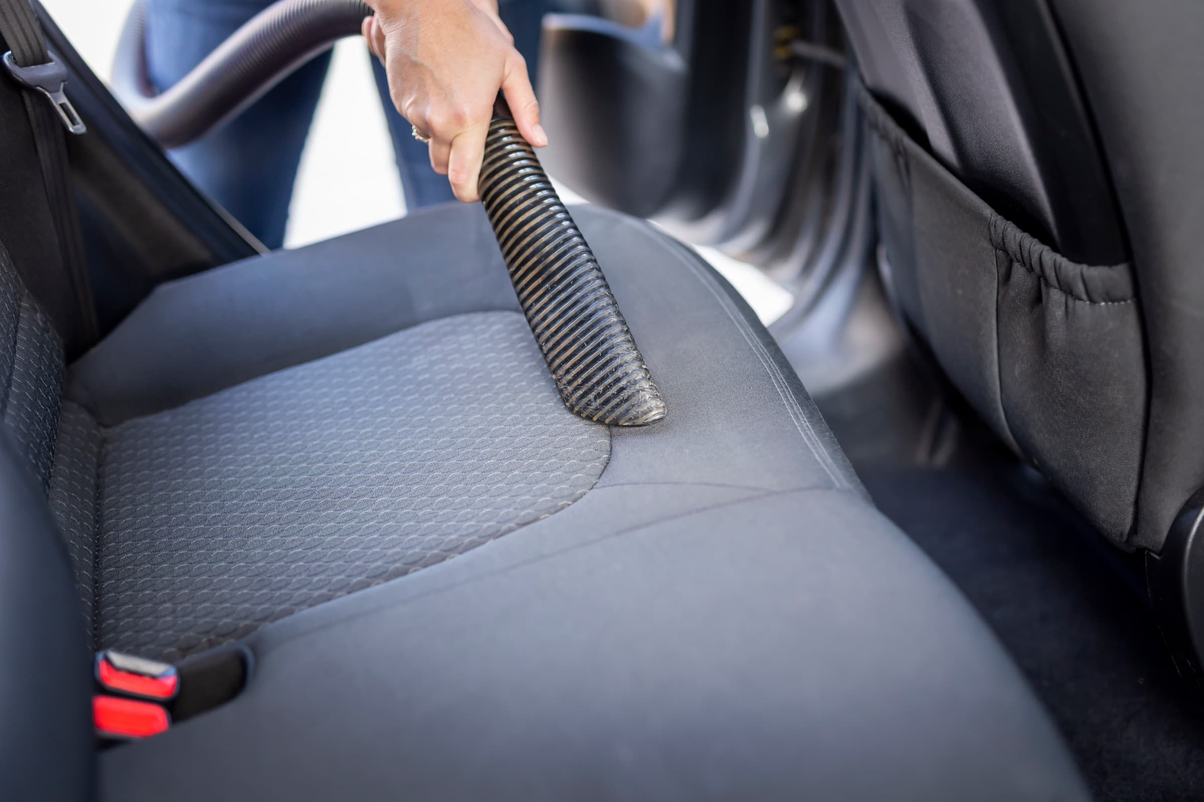 Vacuum hose pulling grit out of a fabric vehicle seat
